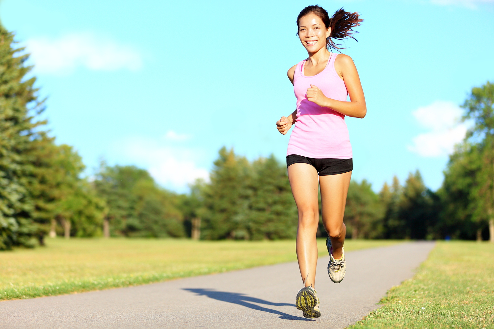 Sport fitness woman running in park on summer day. Asian female