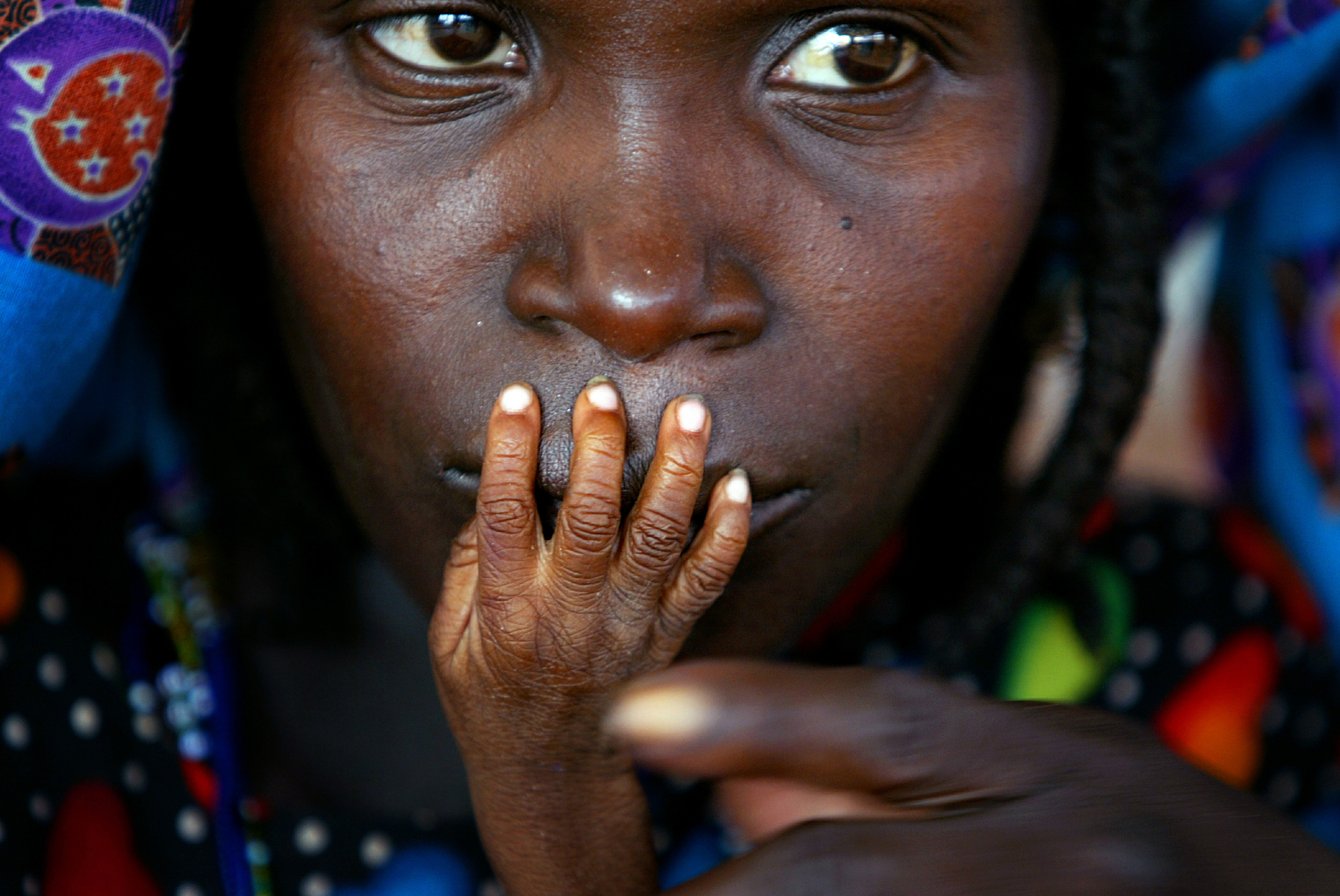 The fingers of malnourished one-year-old Galisou are pressed against the lips of his mother Ousseini at a feeding clinic in Niger