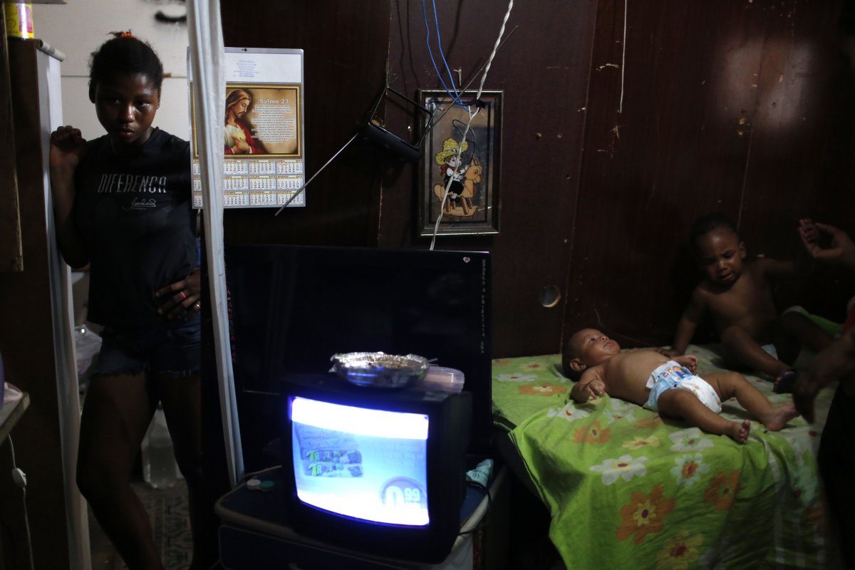 a-babysitter-stands-at-the-entrance-to-a-makeshift-home-within-the-nova-tuffy-slum-of-rio-de-janeiro