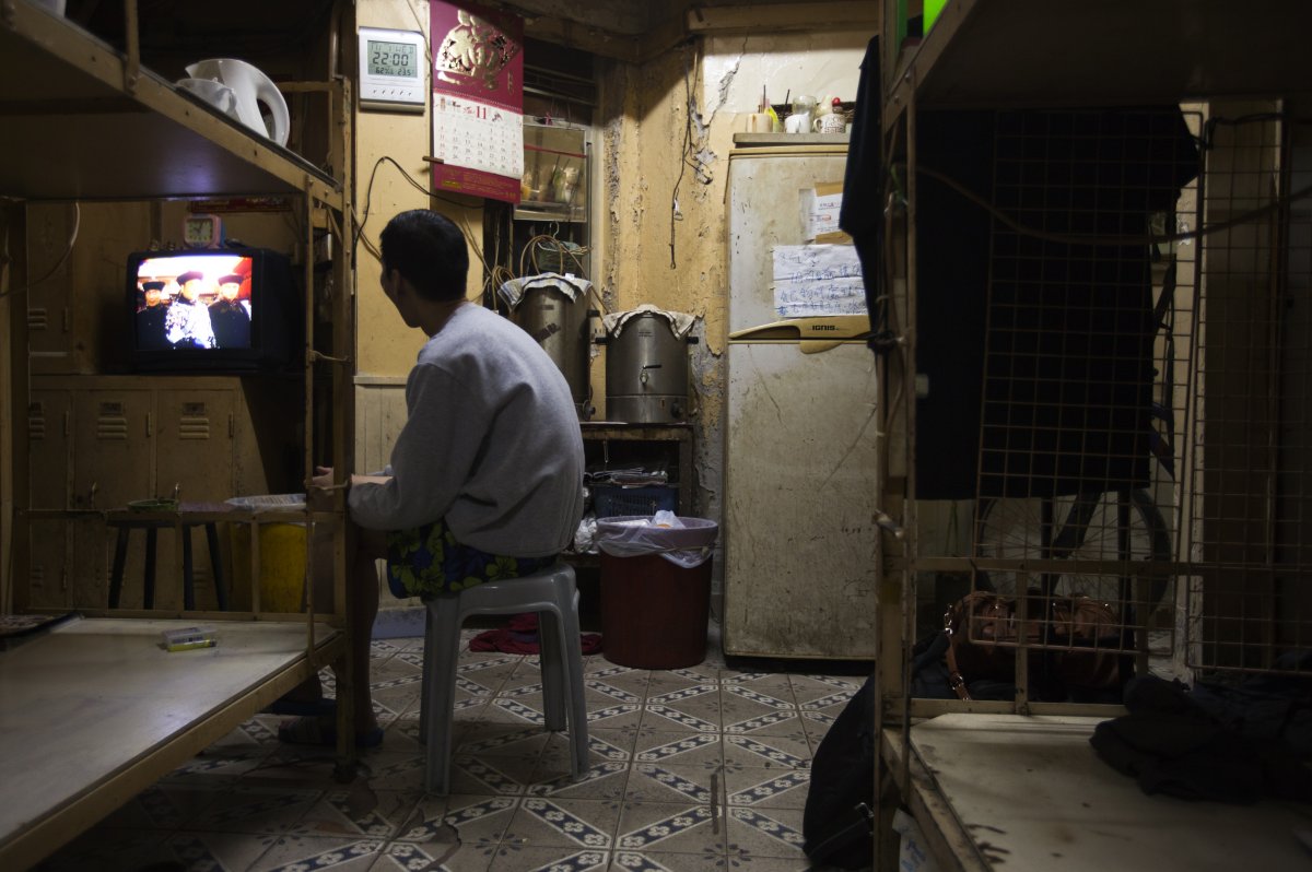 in-front-of-his-bed-in-hong-kong-a-local-watches-tv-in-the-dim-light-of-a-home-that-he-rents-for-167-a-month