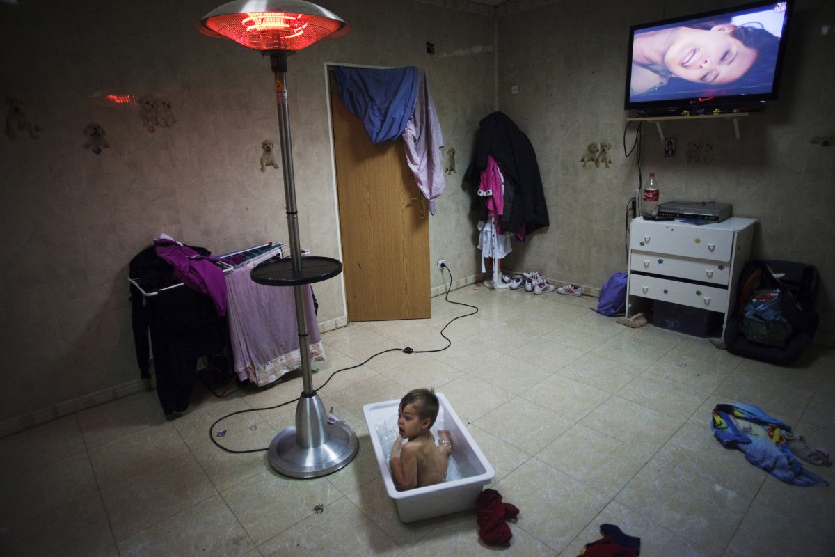 outside-of-madrid-in-the-gypsy-settlement-of-puerta-de-hierro-a-young-boy-takes-a-bath-while-watching-tv-at-his-grandparents-house
