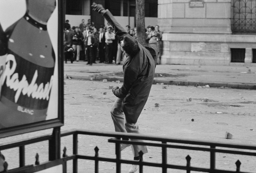 A young man throwing a rock on the boulevard Saint Germain.